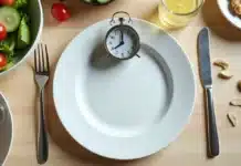 Jejum intermitente: como aplicar com segurança no dia a dia Prato vazio com talheres e relógio simbolizando jejum intermitente em mesa de cozinha saudável